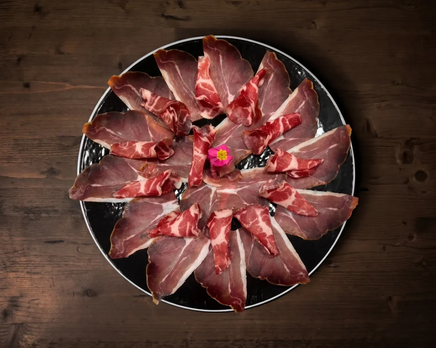 Jamon Serrano tagliato a coltello servito con pane fritto e datterini